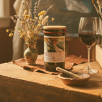 wine Bottle candle of Fiona & Fritz Hippos  with a glass of red wine on a wooden table.